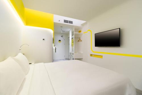 a white room with a bed and a tv on the wall at YELLO Hotel Kuta Beachwalk Bali in Kuta