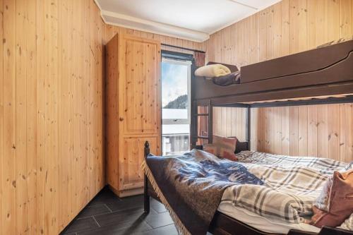 two beds in a room with wooden walls and a window at Hemsedal-leilighet med 3 soverom, 2 bad og badstue in Hemsedal