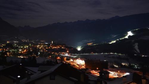 a view of a city at night with mountains at Pozza Appartamenti in Carano