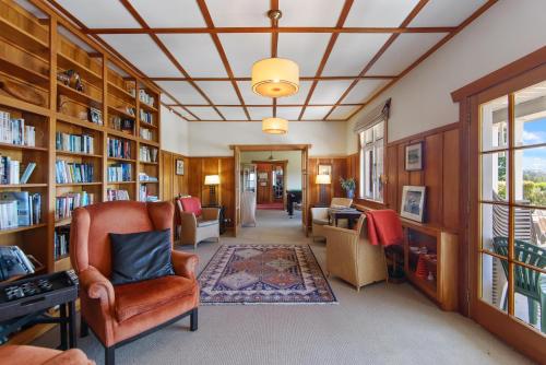 a library with wooden book shelves and a chair at Lake Brunner Eco Lodge in Moana