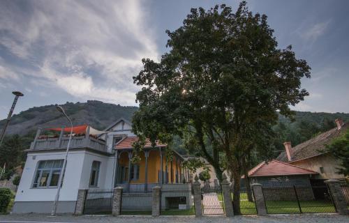 a white and yellow house with a fence and a tree at Anna Vendégház in Visegrád