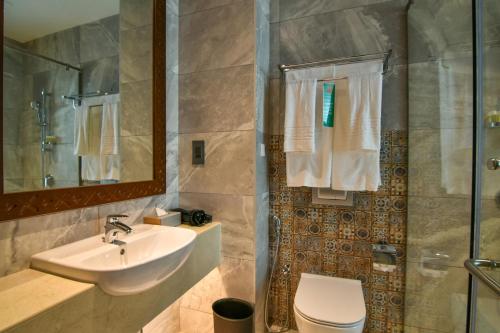 a bathroom with a sink and a toilet and a shower at Golden Tulip Zanzibar Airport Hotel & Spa in Zanzibar City