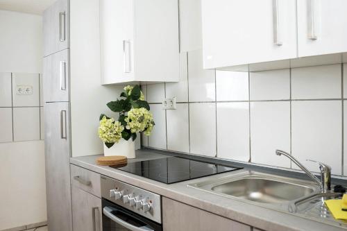 a white kitchen with white cabinets and a sink at Gemütliches Ferienhaus in Burscheid