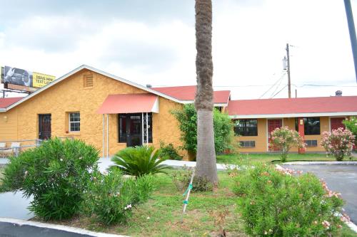 żółty budynek z palmą przed nim w obiekcie El Camino Motel w mieście Beeville