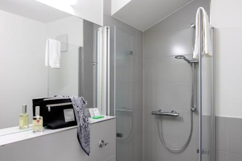 uma casa de banho branca com um chuveiro e um lavatório. em Gästehaus Reckahn der Rochow Akademie em Reckahn