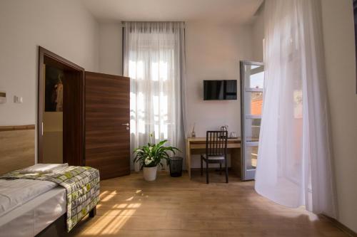 a bedroom with a bed and a desk and a window at Anna Vendégház in Visegrád
