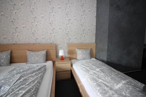 a bedroom with two beds and a table with a lamp at Downtown Apartments in Plzeň
