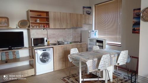 una cucina con lavatrice e tavolo con sedie di DESI HOUSE 101 Cozy Studio Nessebar a Nesebar