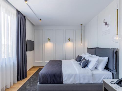 a bedroom with a large bed with white walls at Mövenpick Hotel Lalez Durres in Durrës