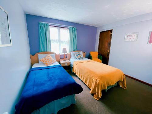 a blue room with two beds and a window at Brookside Lodge in Baldock