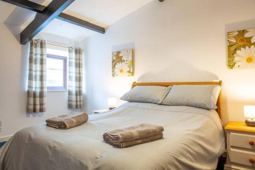 伊爾弗勒科姆的住宿－Hele Bay Cottage，一间卧室配有一张大床和两条毛巾