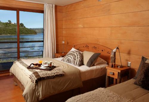 a bedroom with two beds and a large window at Palafito 1326 Hotel Boutique Chiloé in Castro