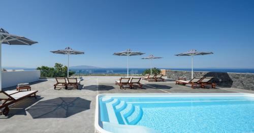 a swimming pool with chairs and umbrellas on a patio at Ianthe Apartments & Villa in Oia