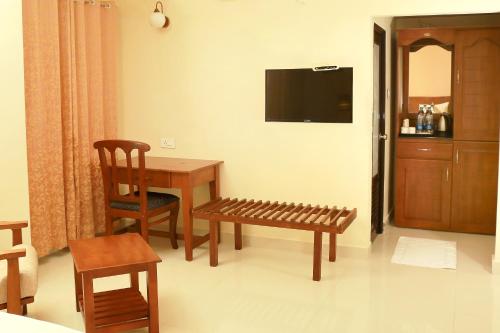 Habitación con mesa, silla y TV. en KTDC Grand Chaithram en Thiruvananthapuram