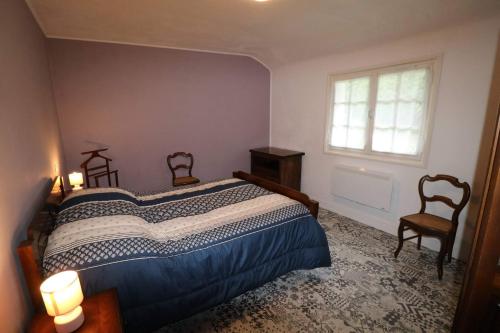 a bedroom with a bed with two chairs and a window at Gîtes du Franc Rosier 2 in Rigny-Ussé