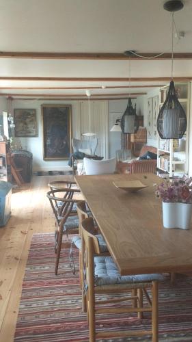 uma sala de jantar com uma grande mesa de madeira e cadeiras em Under Valnødden em Stubbekøbing