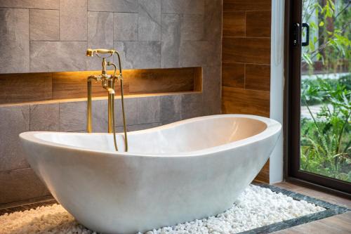 a white bath tub in a bathroom with a window at Bai Dinh Riverside Resort & Spa in Ninh Binh
