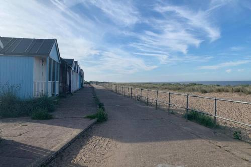 a long sidewalk next to a fence next to a beach at Shore Lodge. 4 bed bungalow only mtrs from the beach. Sleeps 8 in Sutton on Sea
