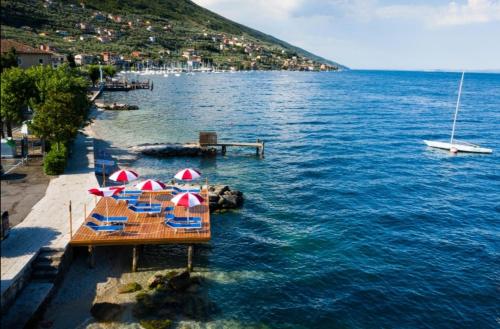 a group of tables with umbrellas in the water at Hotel Luisa in Brenzone sul Garda
