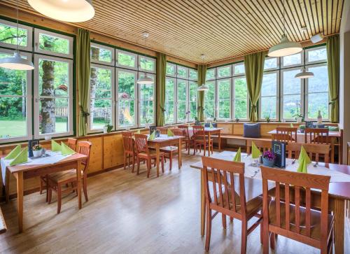 ein Restaurant mit Tischen, Stühlen und Fenstern in der Unterkunft JUFA Hotel Grundlsee in Grundlsee