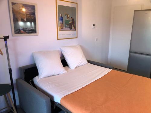 um quarto com uma cama com lençóis brancos e um frigorífico em LE BEL AIR em Pugny-Chatenod