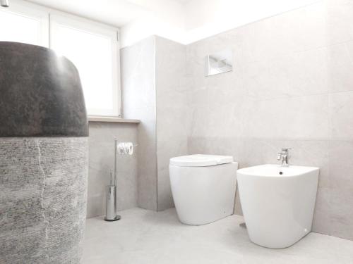 a white bathroom with a toilet and a sink at Principe Rooms in Centola
