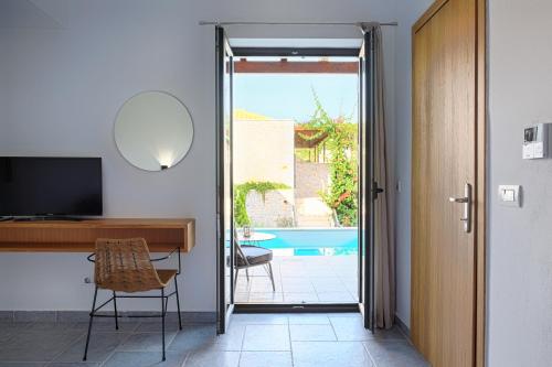 a room with a desk and a television and a pool at Margo Beach Hotel in Gythio