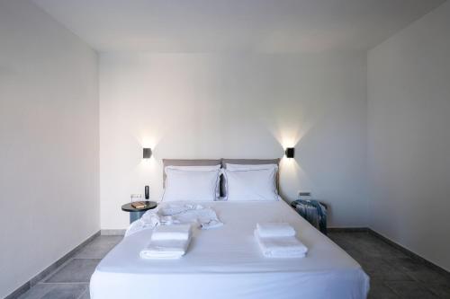a bedroom with a white bed with towels on it at Margo Beach Hotel in Gythio