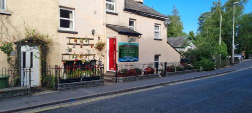 a building with a red door on the side of a street at Holly Cottages in Bowness-on-Windermere