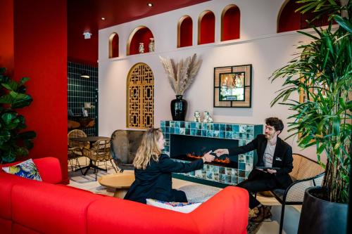 a man and a woman sitting in front of a fireplace at Aiden by Best Western Lorient Centre in Lorient