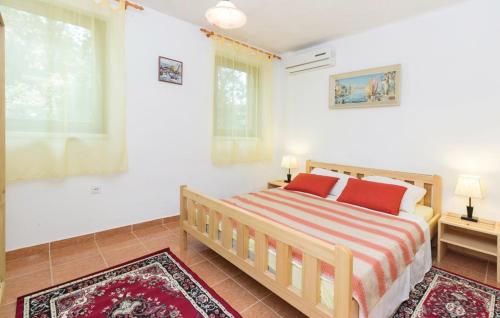 a bedroom with a bed with two red pillows at Apartmani Čižmešija in Tkon