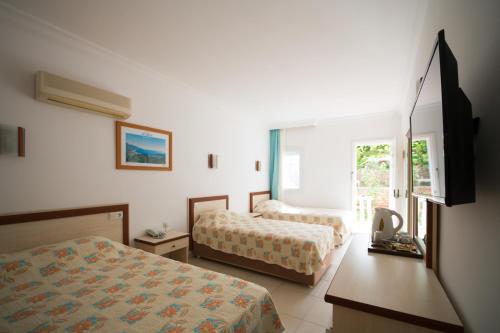 a hotel room with two beds and a television at Oludeniz Turquoise Hotel - All Inclusive in Oludeniz