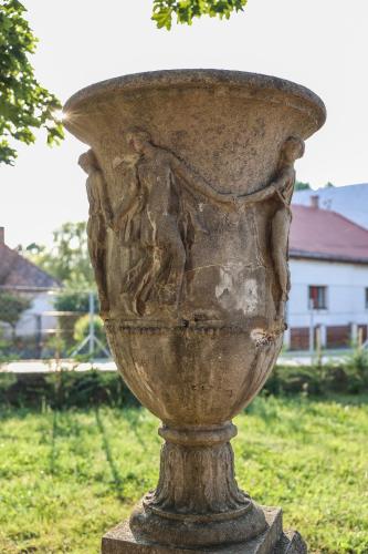 a stone vase sitting on top of a field at Szarvas apartman - Jakuzzis Vendégház Mány in Mány