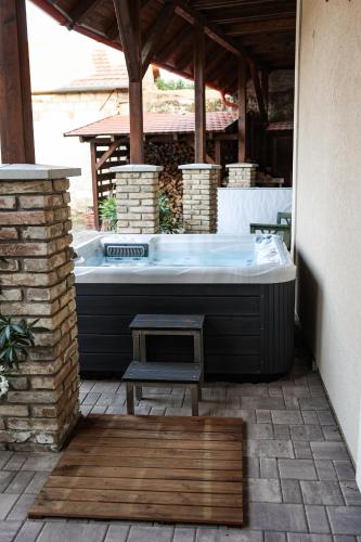a hot tub sitting on a patio with a bench at Szarvas apartman - Jakuzzis Vendégház Mány in Mány