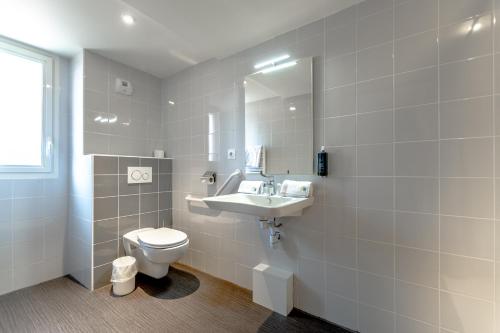 a white bathroom with a toilet and a sink at Hotel Le Virevent in Saint-Raphaël
