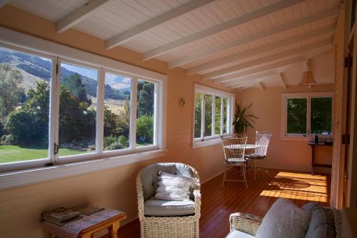 a living room with windows and a table and chairs at Kaituna Valley Homestead in Little River