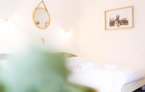 a white bedroom with a bed and a mirror at Hotel Bistrot FINE in Anglet