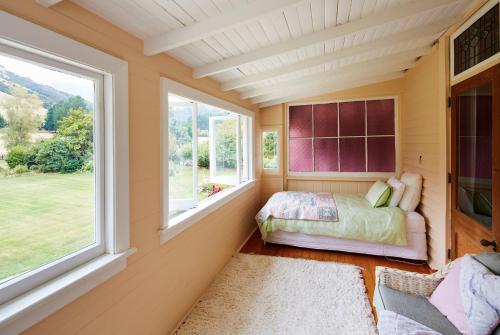 a bedroom with a bed and two windows at Kaituna Valley Homestead in Little River