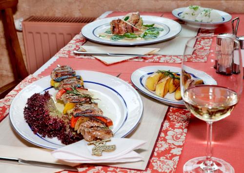 a table with plates of food and a glass of wine at Wellness Hotel Ida in Františkovy Lázně