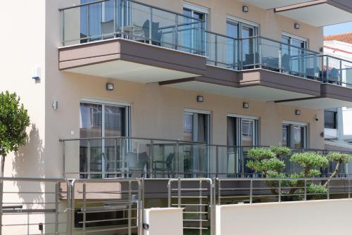ein Apartmenthaus mit Balkonen, Tischen und Stühlen in der Unterkunft Crist Luxury Apartments in Nea Potidaea