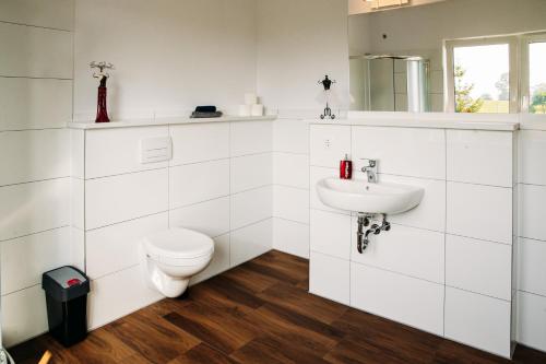 a white bathroom with a toilet and a sink at Apartament Antonia in Sarnowy