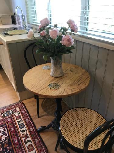 a table with a vase of pink flowers on it at Little Banks Cabin in Ringwood