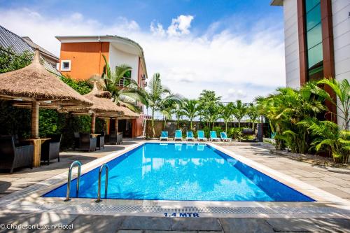 una piscina en un complejo con sillas y sombrillas en Charleson Luxury Hotel, en Port Harcourt