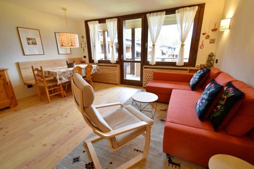 a living room with a red couch and a table at RIO FALZE' Wood in Madonna di Campiglio