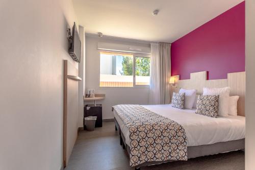 a bedroom with a large bed with a purple wall at Hotel Le Virevent in Saint-Raphaël
