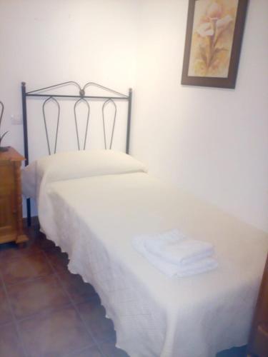 Un dormitorio con una cama blanca y una foto en la pared en Casa Rural del Médico I y II, en Herradón de Pinares