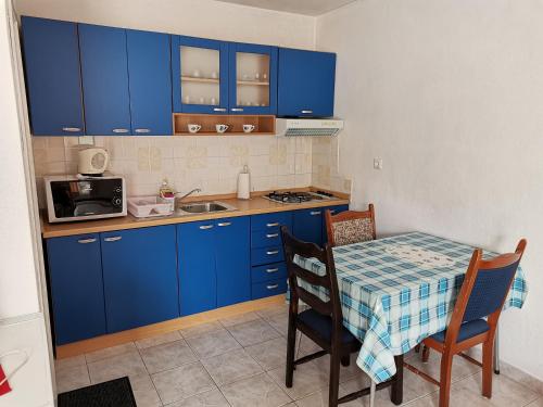 una pequeña cocina con armarios azules y una mesa con sillas. en Apartments Radonic, en Hvar