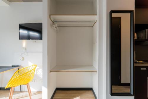 a room with a closet and a yellow chair at Nena Apartments - Kreuzberg 61 in Berlin