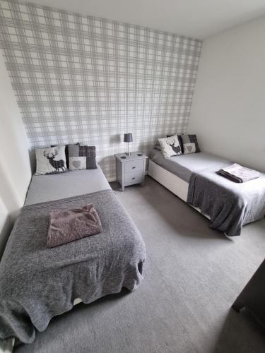 a bedroom with two beds and a night stand at Bespoke Tours Scotland Accommodation @ Morrison Street in Edinburgh