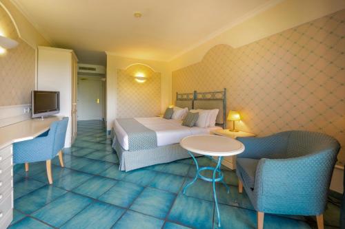 a hotel room with a bed and a table and chairs at Hotel Santa Gilla in Capoterra